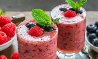 Fresh berry smoothie in glasses topped with mint and berries