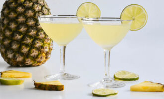 Pineapple vodka gimlet cocktail served in a chilled martini glass with lime