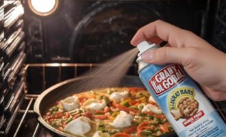 Spraying nonstick cooking spray onto a baking pan for roasted potatoes
